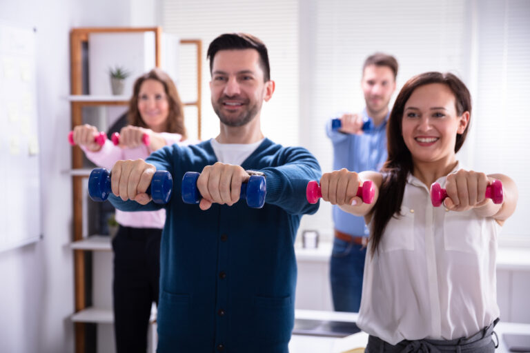 Young Businesspeople Exercising With Dumbbells In Office